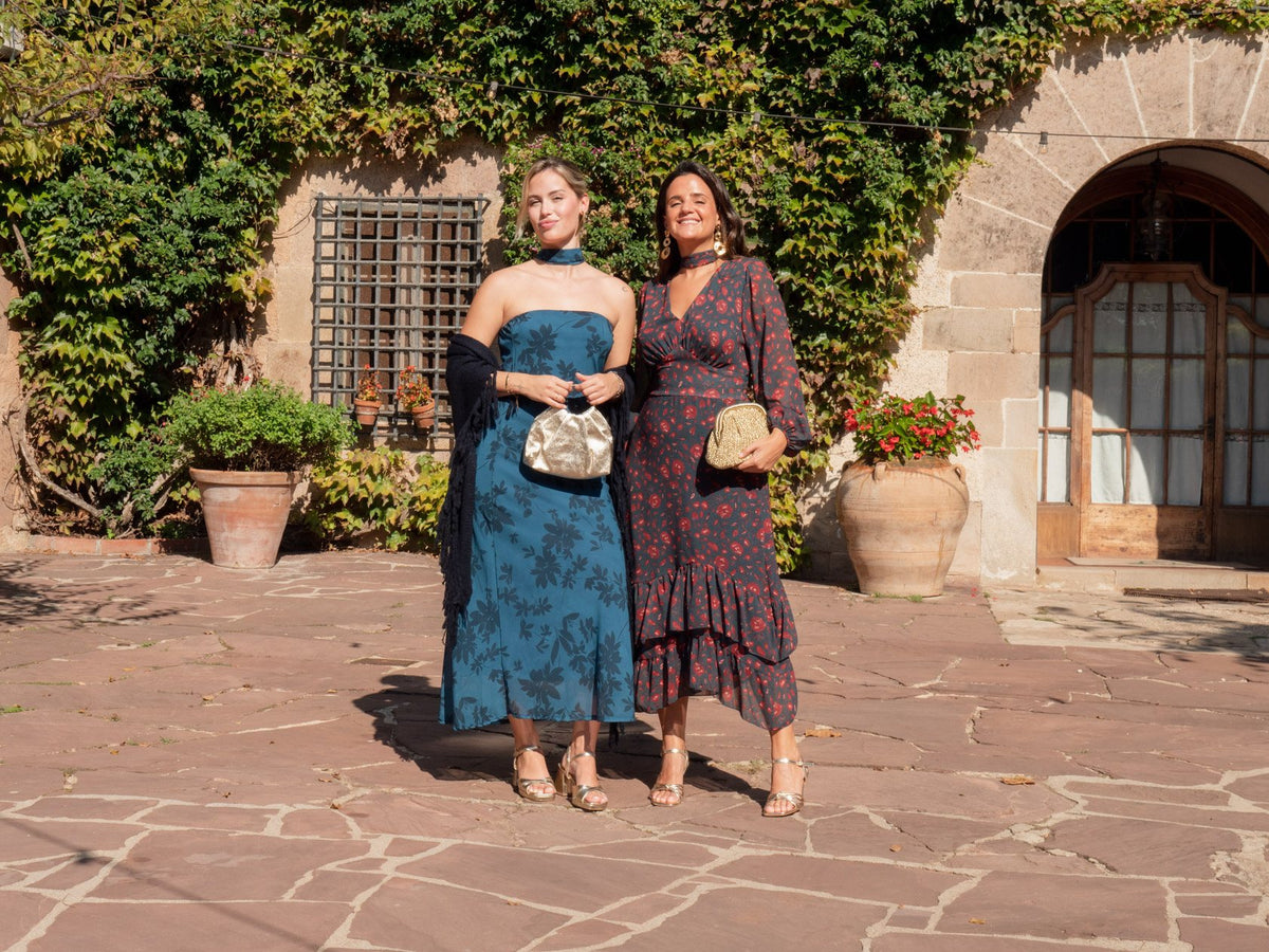 Dos invitadas con vestidos estampados en un patio con hiedra